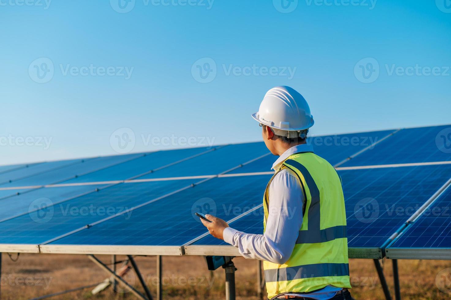 Young engineer use smartphone while working at solar farm photo