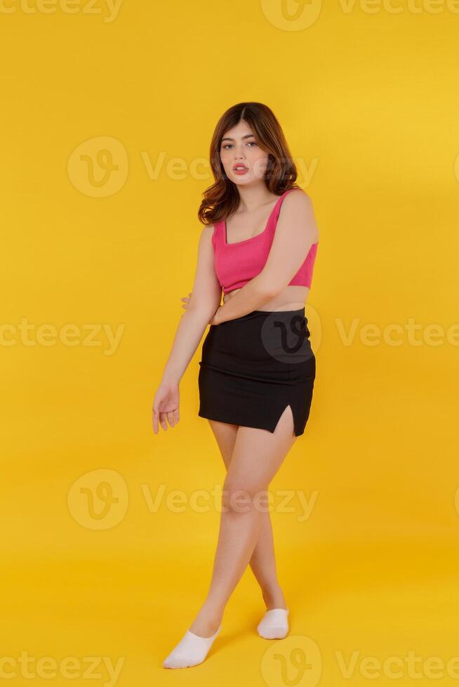 Full length portrait of a beautiful young woman posing isolated over yellow background photo
