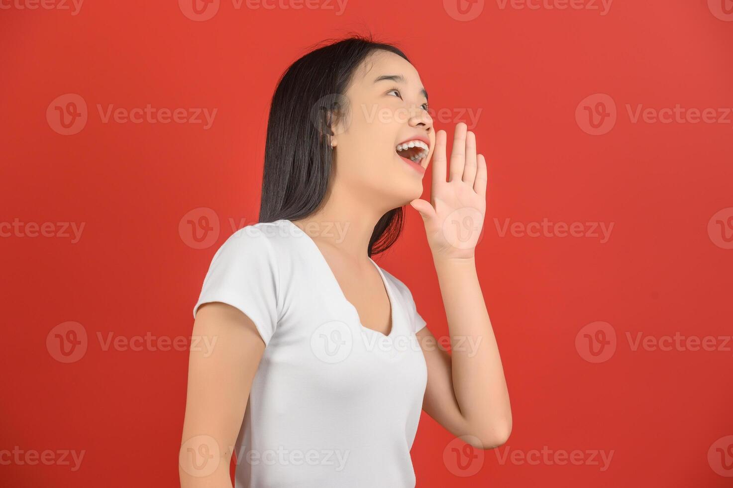 Portrait of Excited young asian woman in white t-shirt shout story or making announcement over isolated white background photo