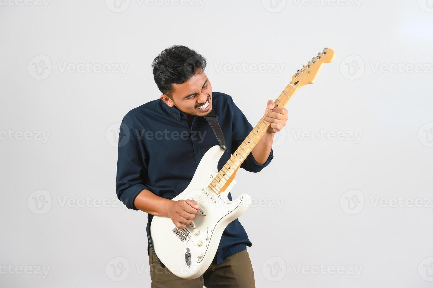 retrato de un joven asiático con camisa azul y guitarra electrónica aislado de fondo blanco foto