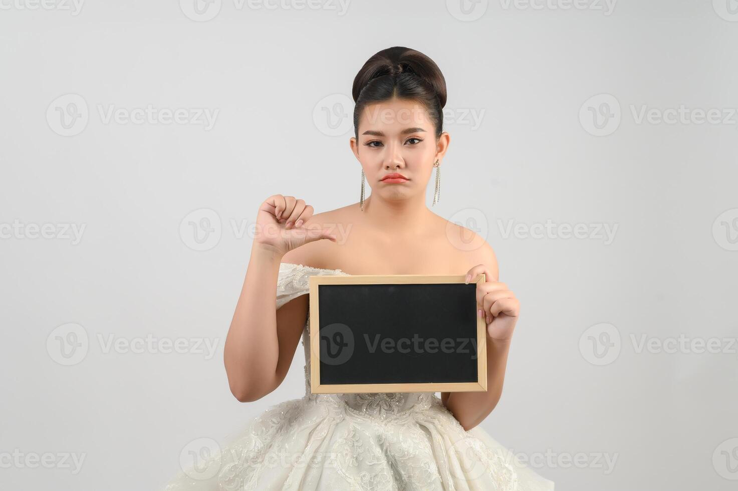 Young asian beautiful bride pose with blank blackboard in hand photo