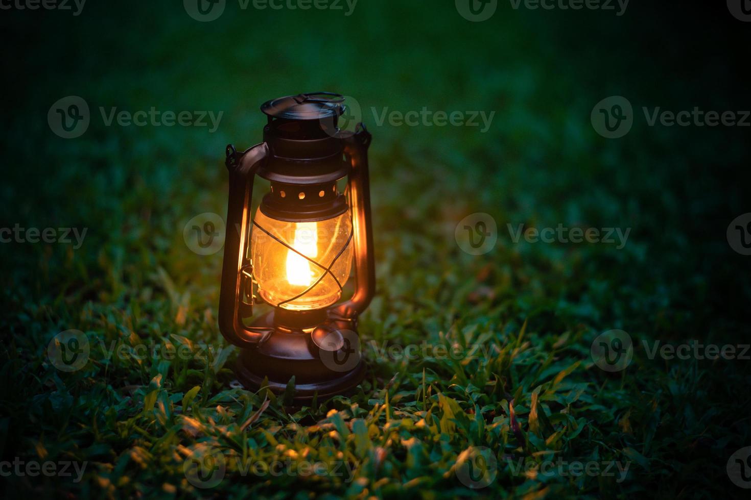 lámpara de aceite antigua en la hierba en el bosque en la noche ambiente de camping.imagen de concepto de viaje al aire libre foto