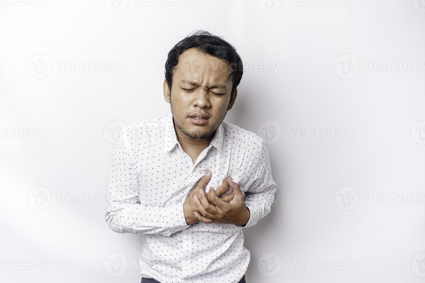 Tired upset young man wears white shirt suffering from pain, muscle spasm at workplace. Fatigue, deadline, pain and incorrect posture photo