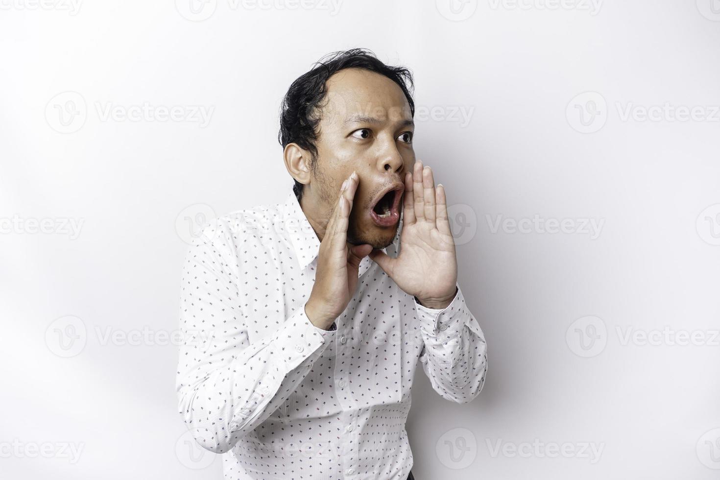 Young handsome man wearing a white shirt shouting and screaming loud with a hand on his mouth. communication concept. photo