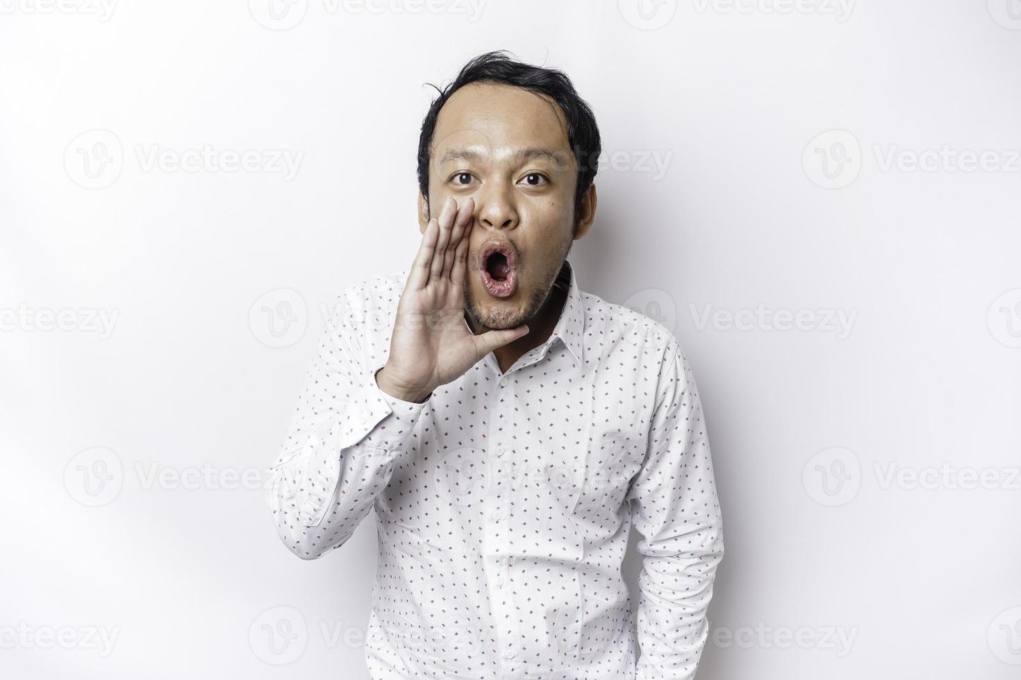 Young handsome man wearing a white shirt shouting and screaming loud with a hand on his mouth. communication concept. photo