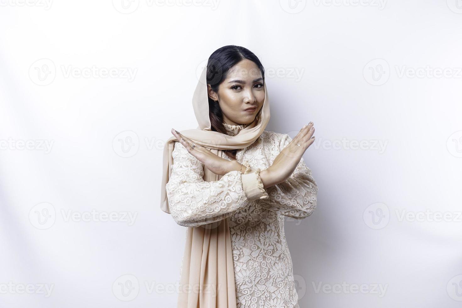 Beautiful Asian Muslim woman wearing a hijab with hand gesture pose rejection or prohibition with copy space photo