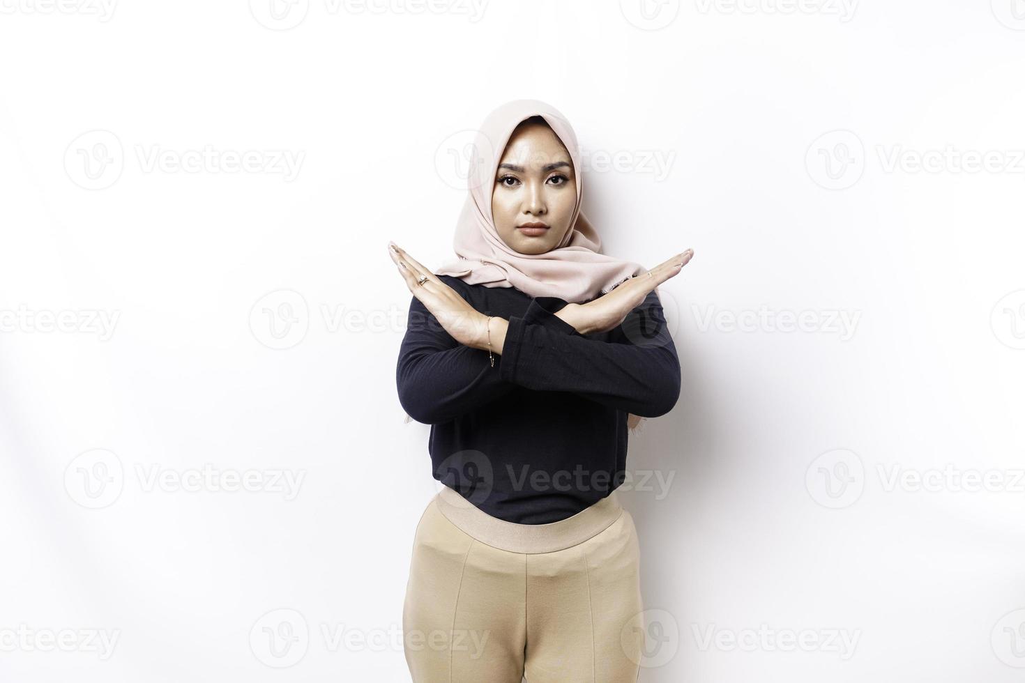 Beautiful Asian Muslim woman wearing a hijab with hand gesture pose rejection or prohibition with copy space photo