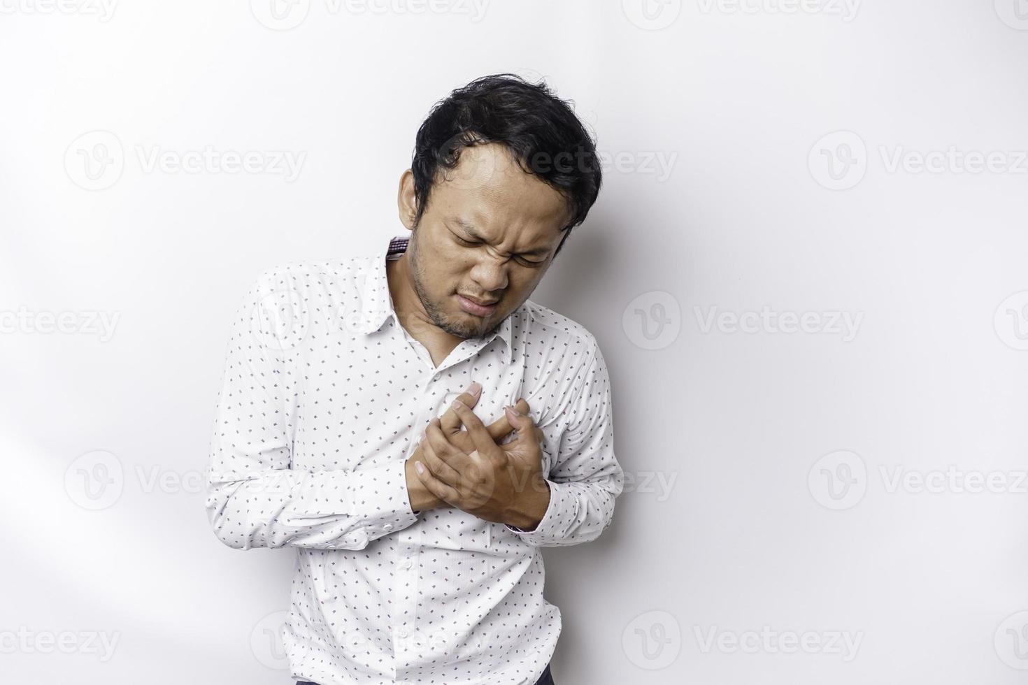 Tired upset young man wears white shirt suffering from pain, muscle spasm at workplace. Fatigue, deadline, pain and incorrect posture photo