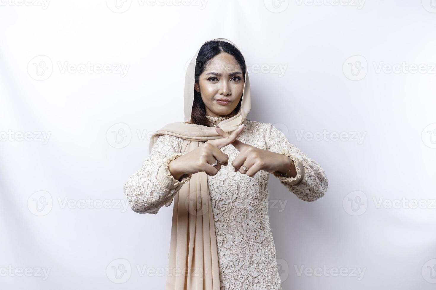 Beautiful Asian Muslim woman wearing a hijab with hand gesture pose rejection or prohibition with copy space photo