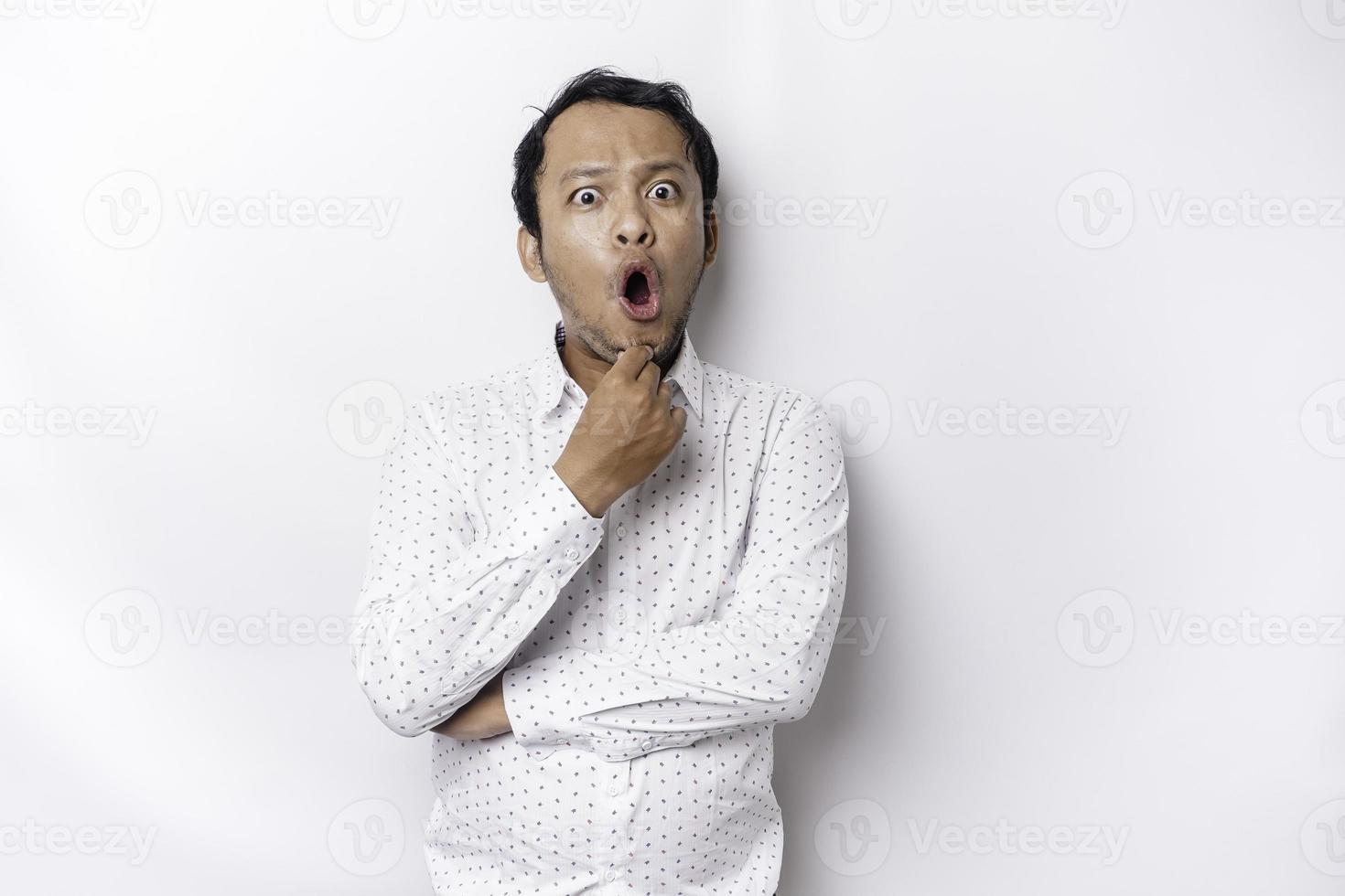 conmocionado asiático hombre con su boca amplio abierto vistiendo blanco camisa, aislado por un blanco antecedentes foto