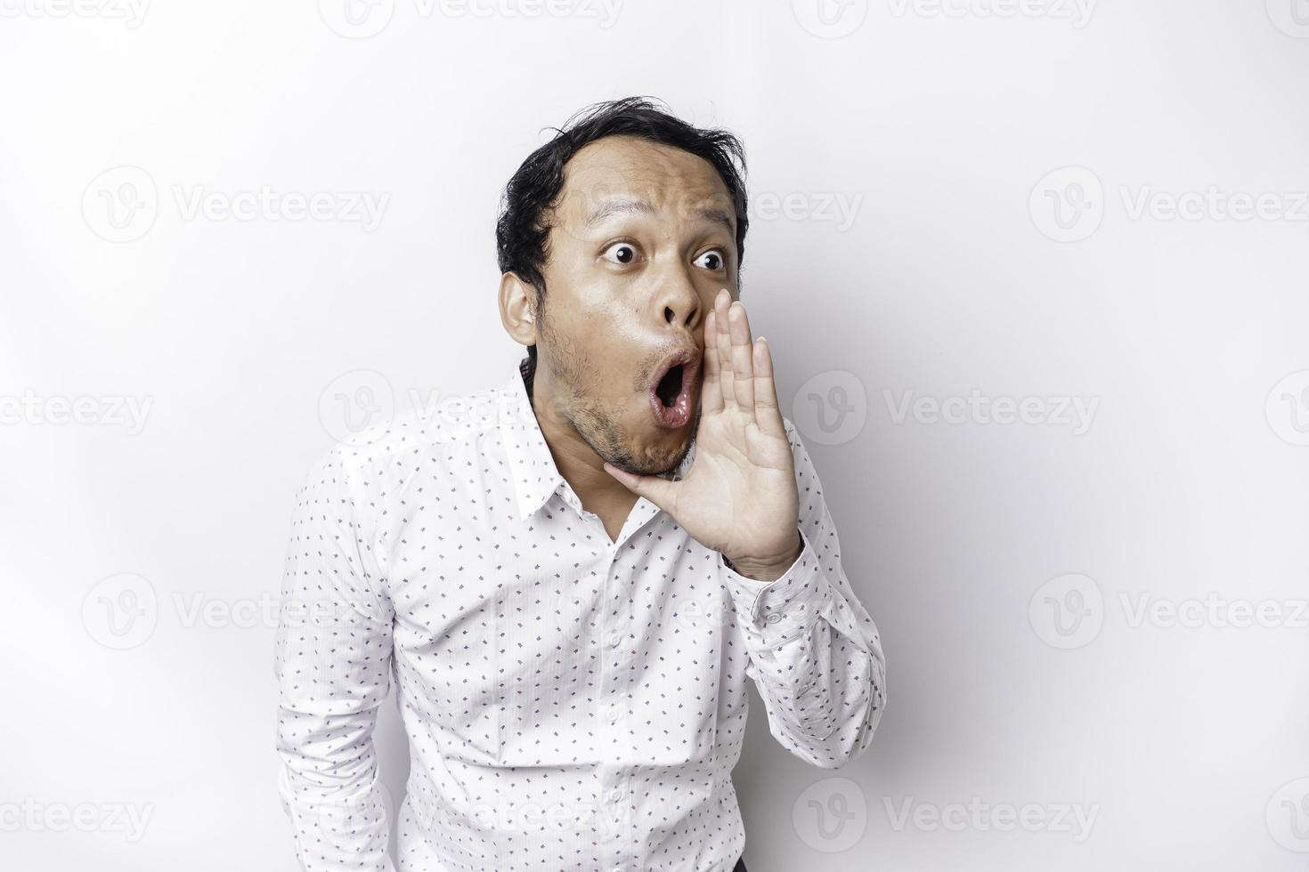 Young handsome man wearing a white shirt shouting and screaming loud with a hand on his mouth. communication concept. photo