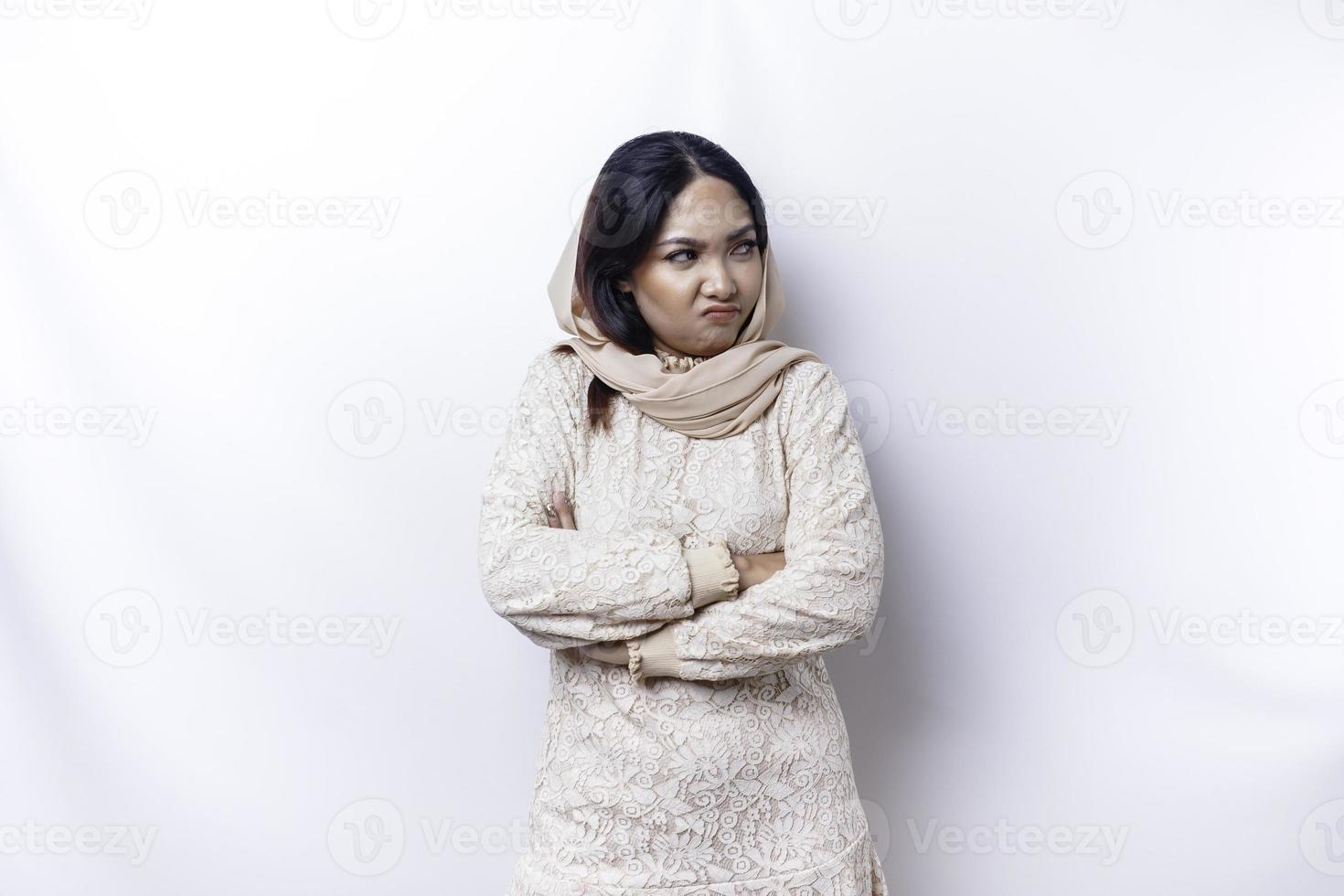 un insatisfecho joven asiático musulmán mujer mira a el cámara posando en un blanco fondo, descontento niña con irritado cara expresiones espectáculo negativo actitud foto