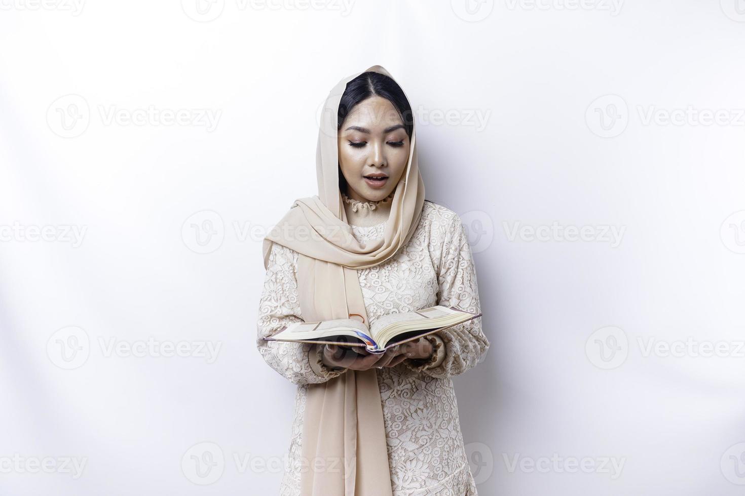 Young Asian Muslim woman smiling and holding the Quran photo