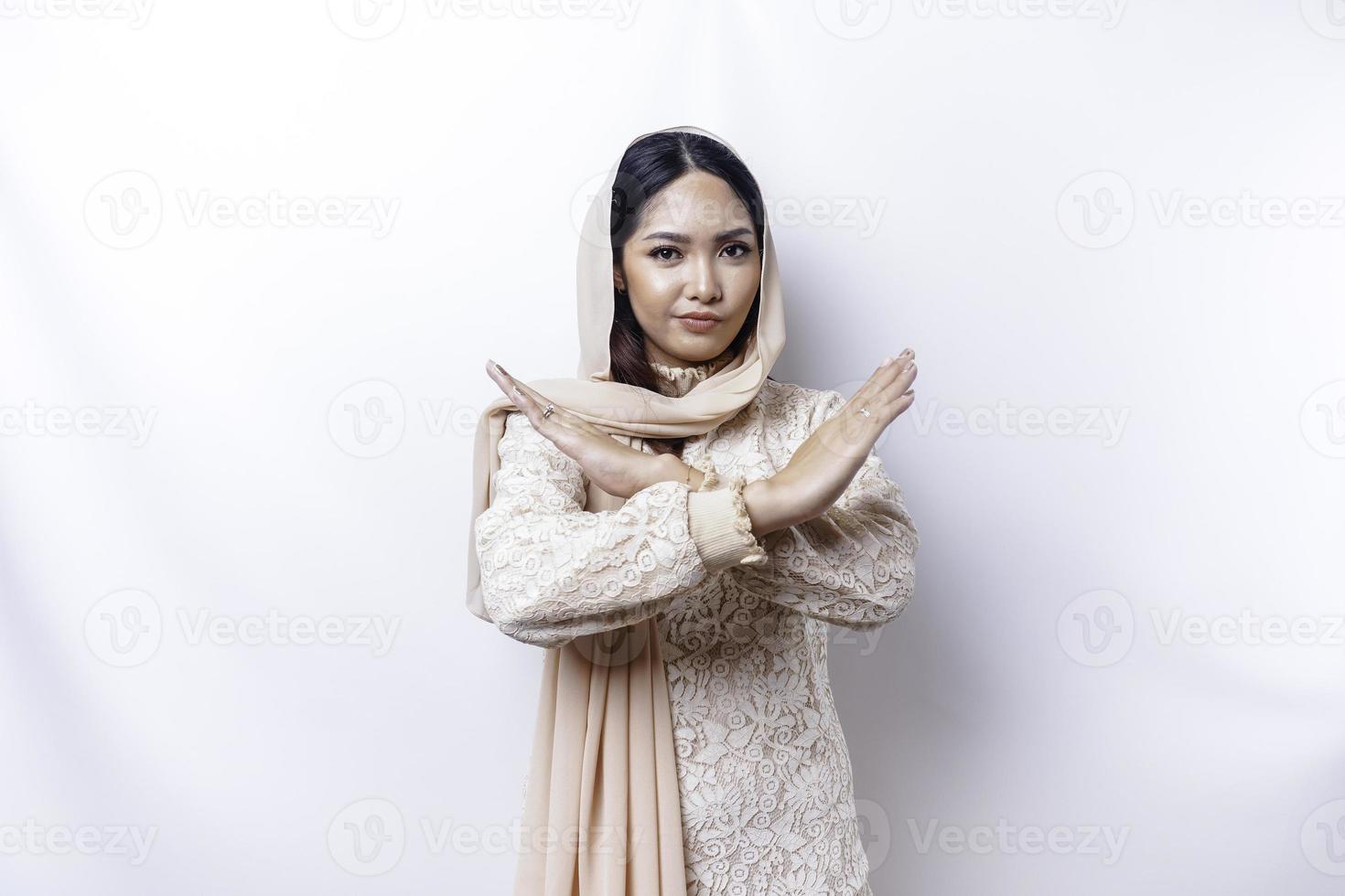 Beautiful Asian Muslim woman wearing a hijab with hand gesture pose rejection or prohibition with copy space photo