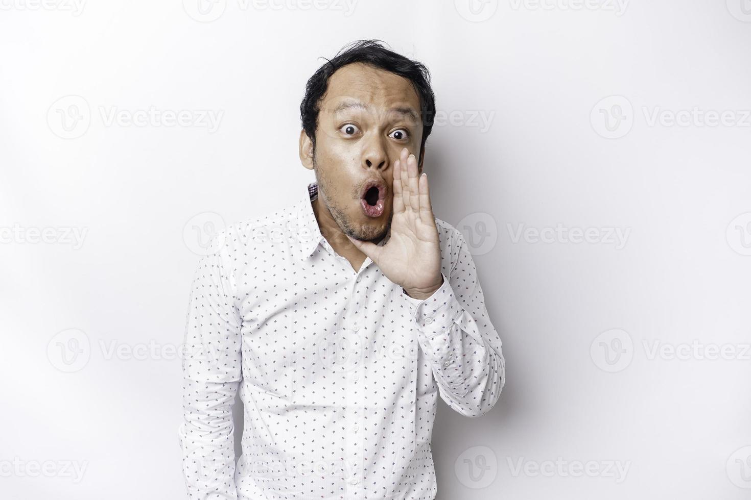 Young handsome man wearing a white shirt shouting and screaming loud with a hand on his mouth. communication concept. photo