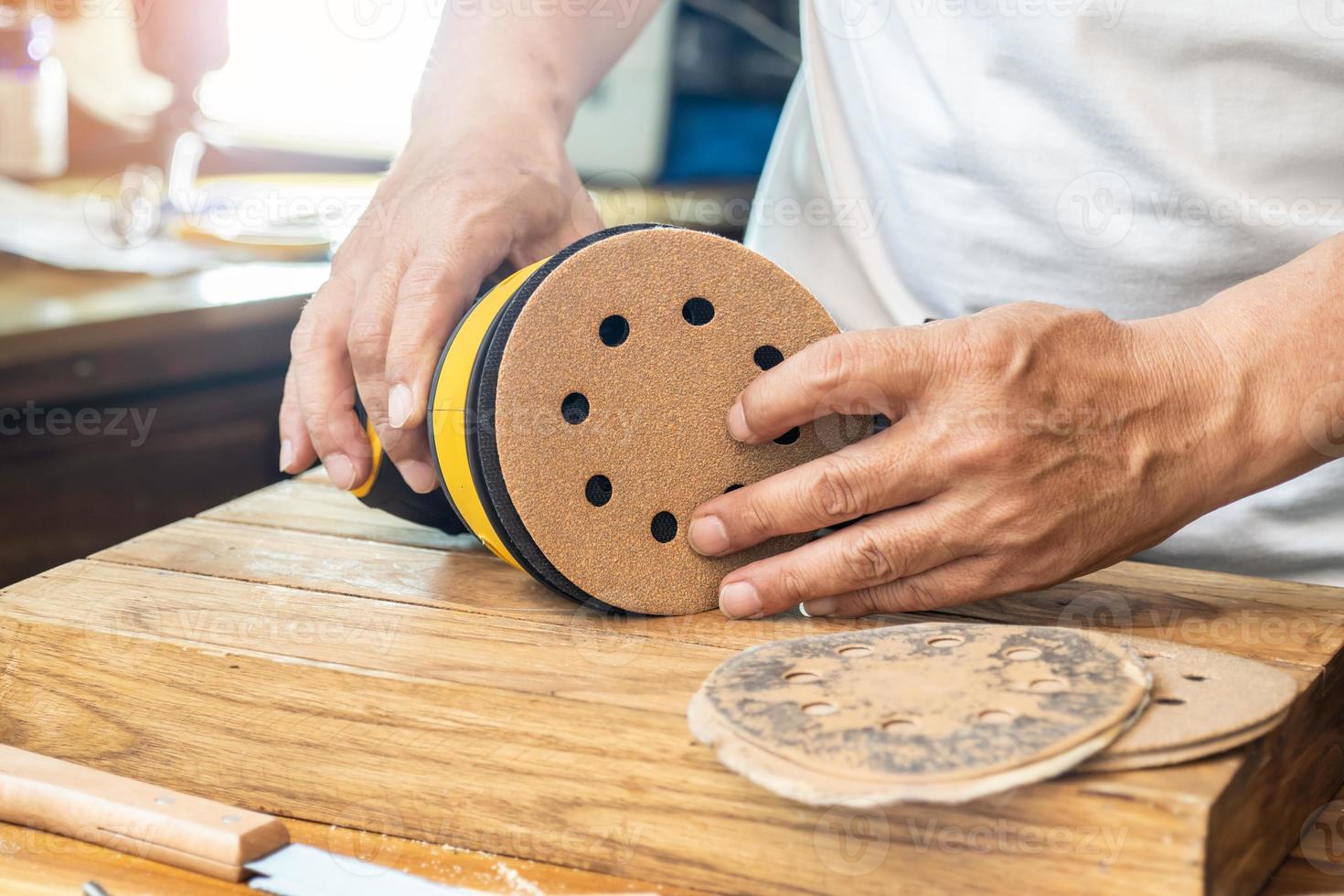 Carpenter attach sandpaper to an orbital sander or palm sander after remove the paper backing of the sandpaper.DIY maker and woodworking concept. selective focus photo