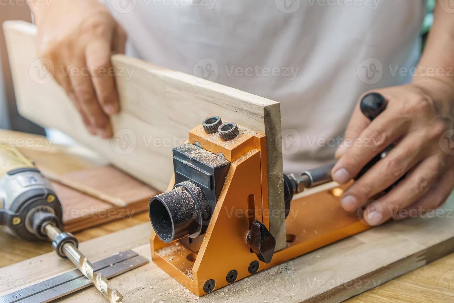 Carpenter use drill bit Pocket hole joinery, or pocket screw joinery, involves drilling a hole at an angle ,make strong joints on wooden plate. D.I.Y and woodworking concept.selective focus. photo