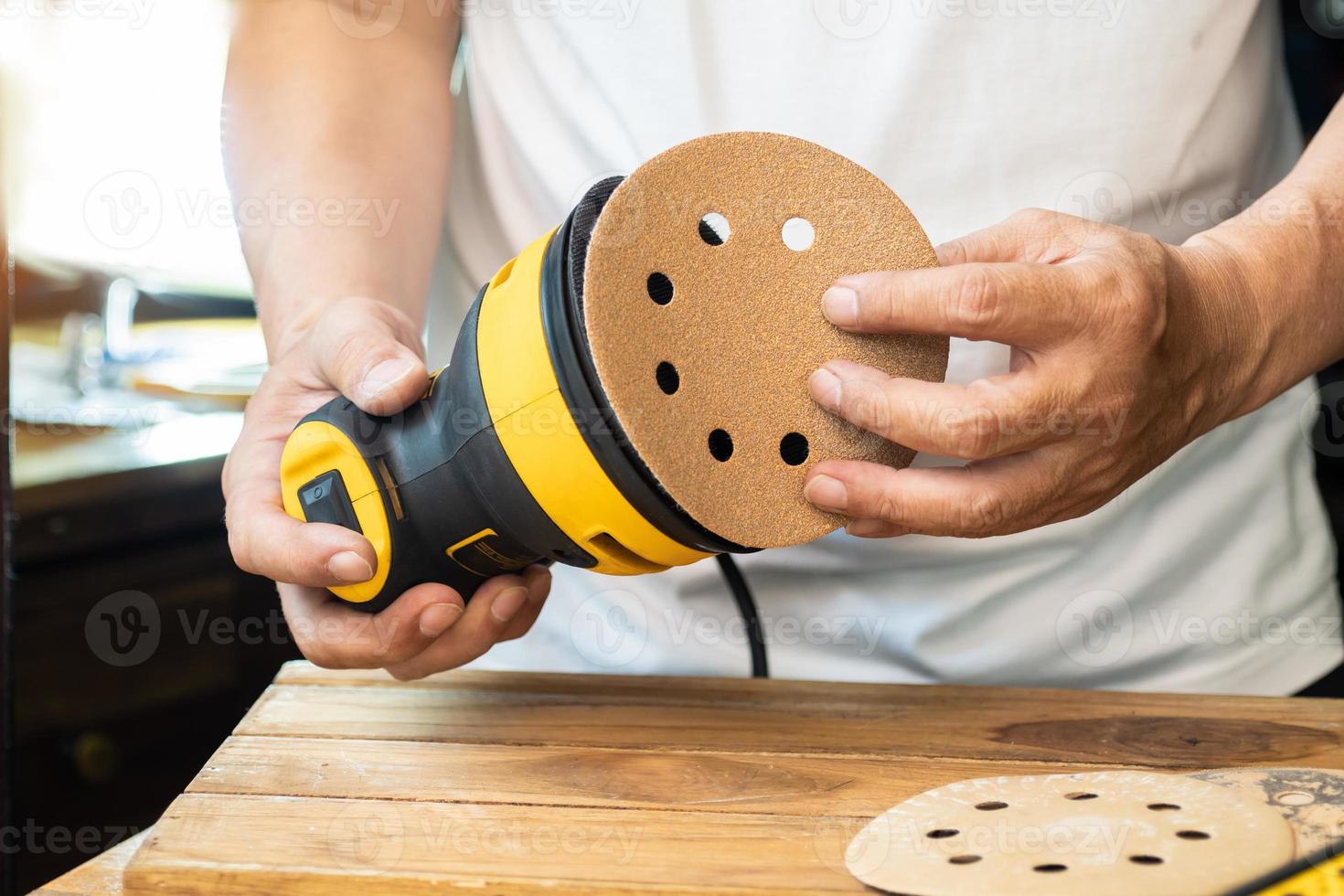 Carpenter attach sandpaper to an orbital sander or palm sander after remove the paper backing of the sandpaper.DIY maker and woodworking concept. selective focus photo