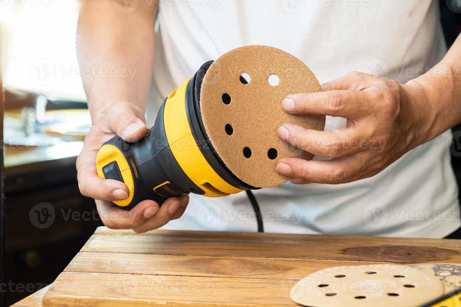 Carpenter attach sandpaper to an orbital sander or palm sander