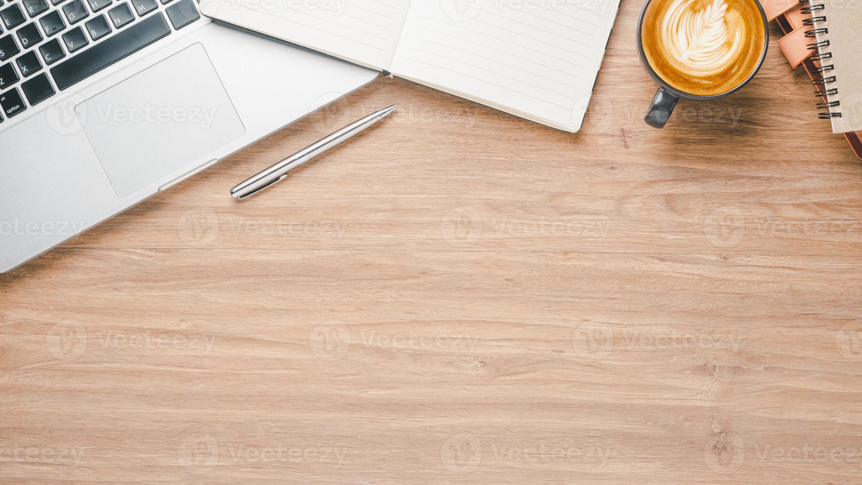 Wooden desk workplace with laptop computer, notebook, pen and cup of coffee, Top view flat lay with copy space. photo