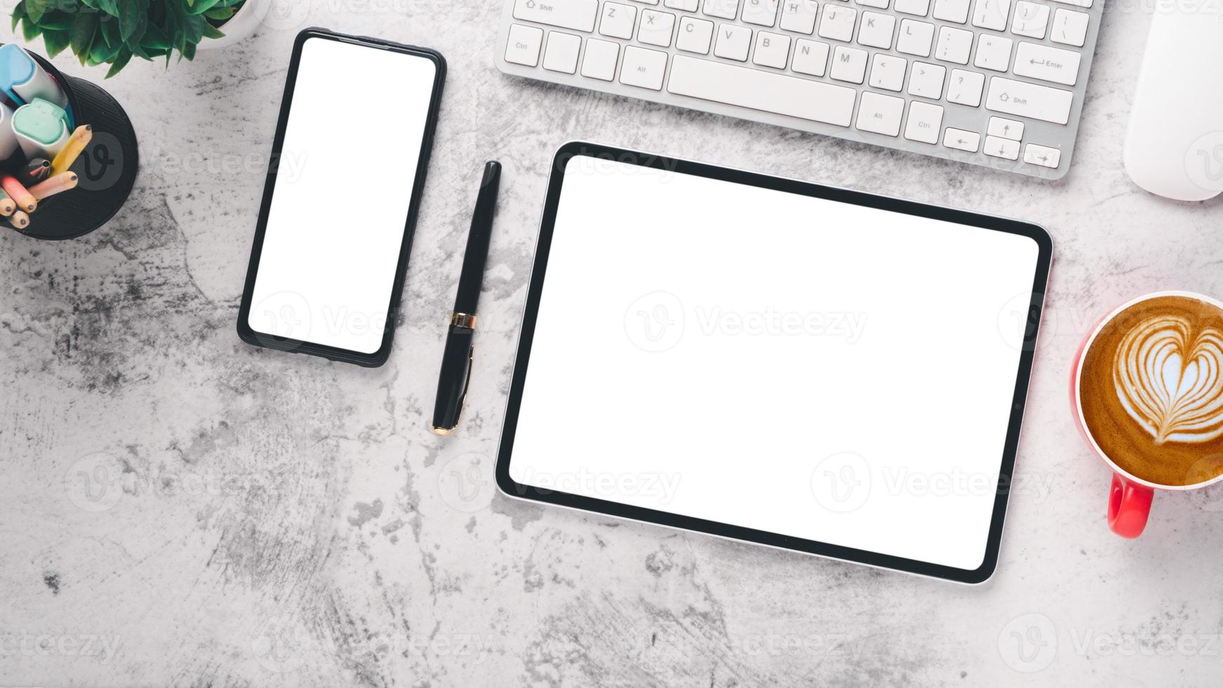 White desk workplace with blank screen tablet and smart phone, keyboard, mouse, pen and cup of coffee, Top view flat lay. photo