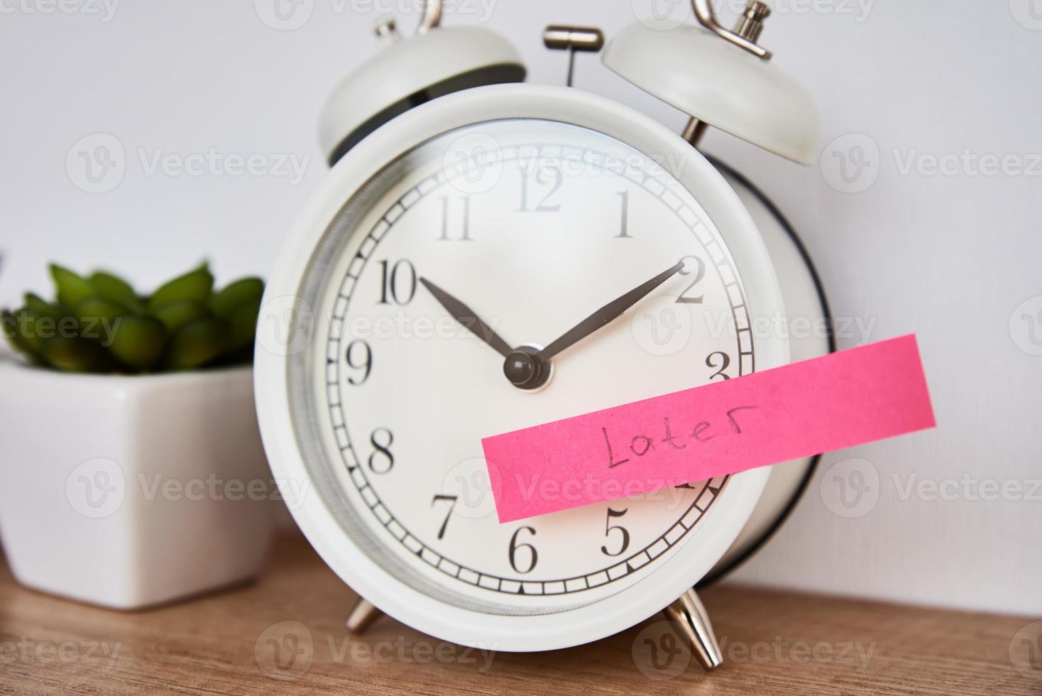 Sticky note with word later on white alarm clock. photo