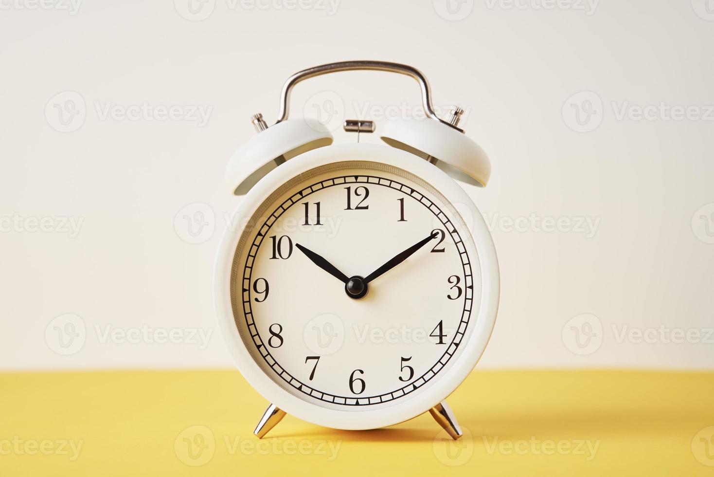 blanco Clásico alarma reloj en un amarillo antecedentes con Copiar espacio foto
