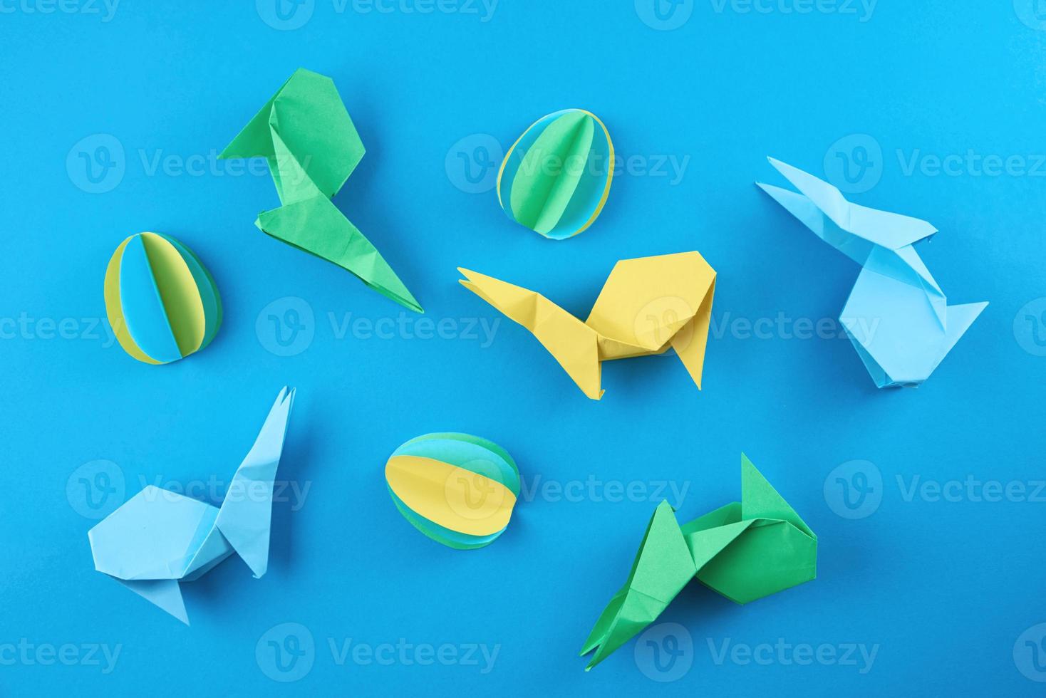 Paper origami Esater rabbits and colored eggs on blue background photo