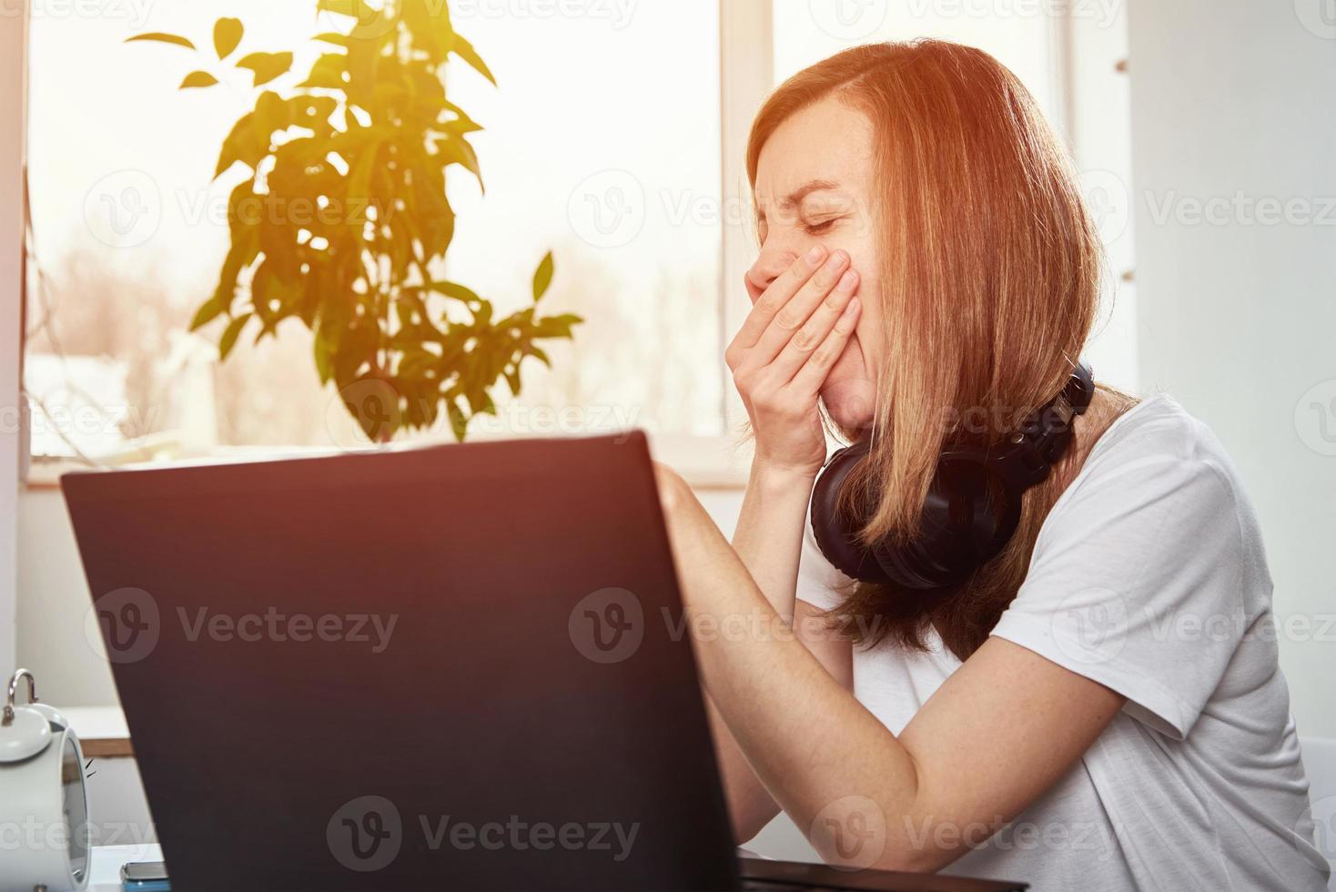 Tired freelancer woman sitting at workplace and procrastinating photo