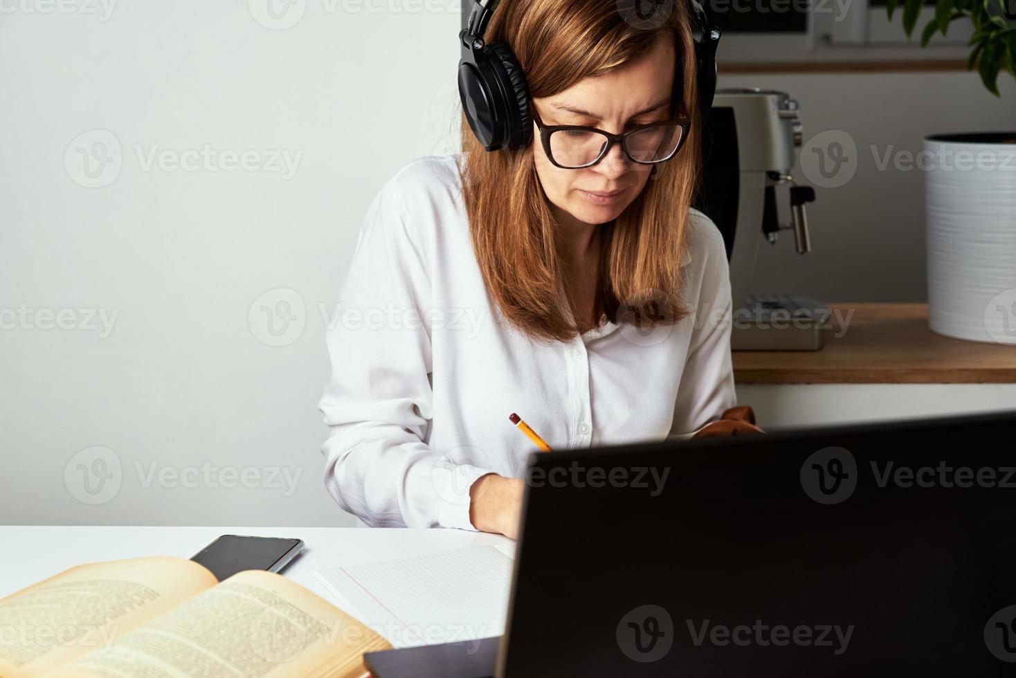 Woman in headphones listen audio course at laptop photo