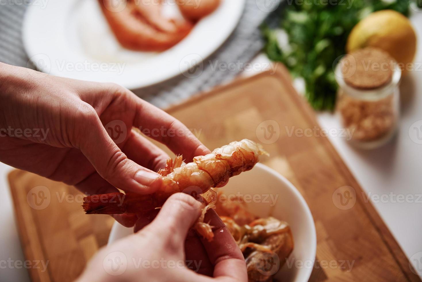 Woman cleaning shrimps for cooking. Process of hands peel shrimps shell photo