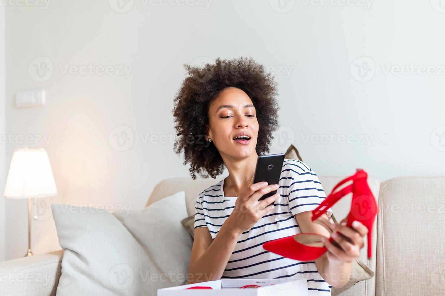 Young woman feeling excited with a new shoes, unpacking purchases and taking photo with phone at home. posting them on social media