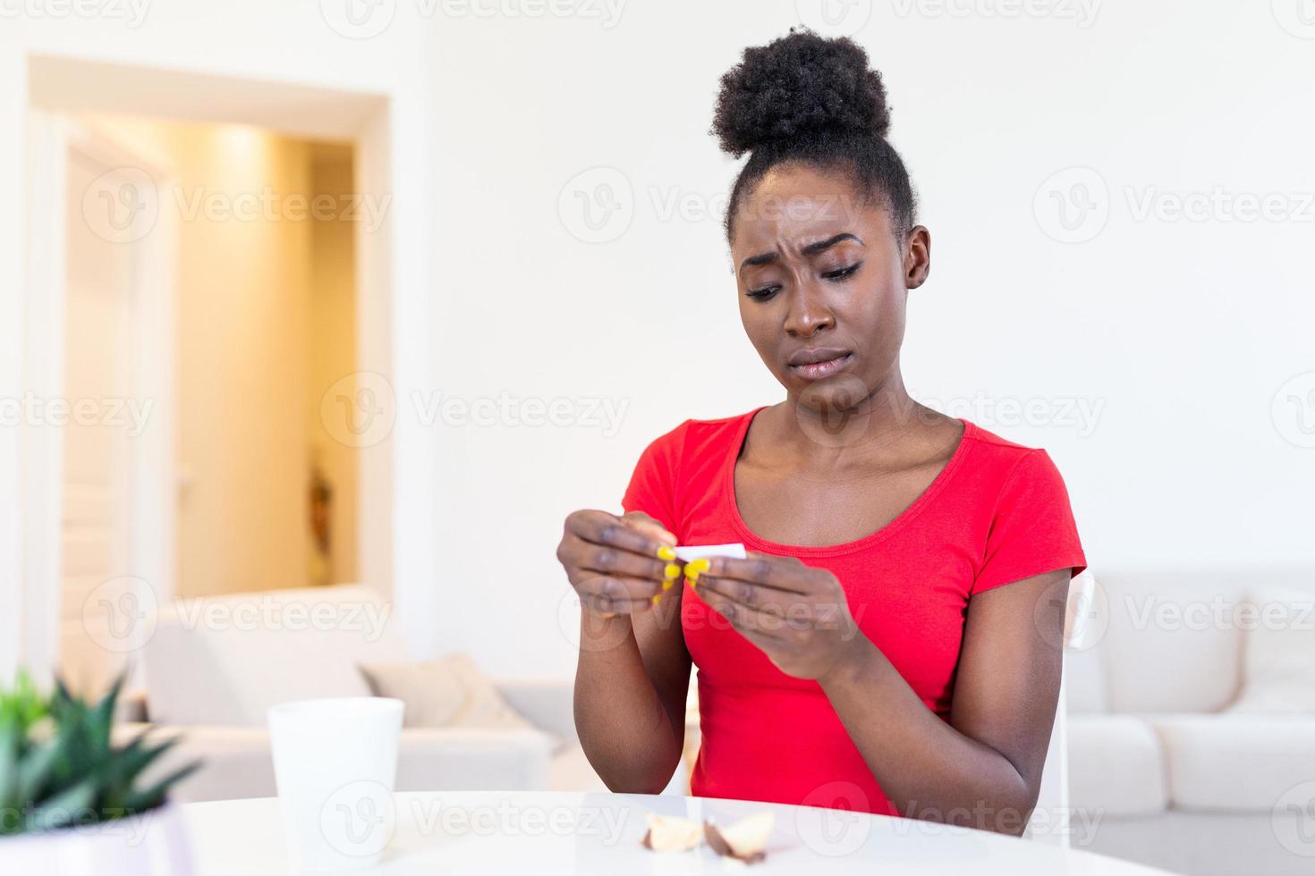 Young african american woman is reading a message from Fortune cookies, does the paper inside of the cookies tell you good things or photo