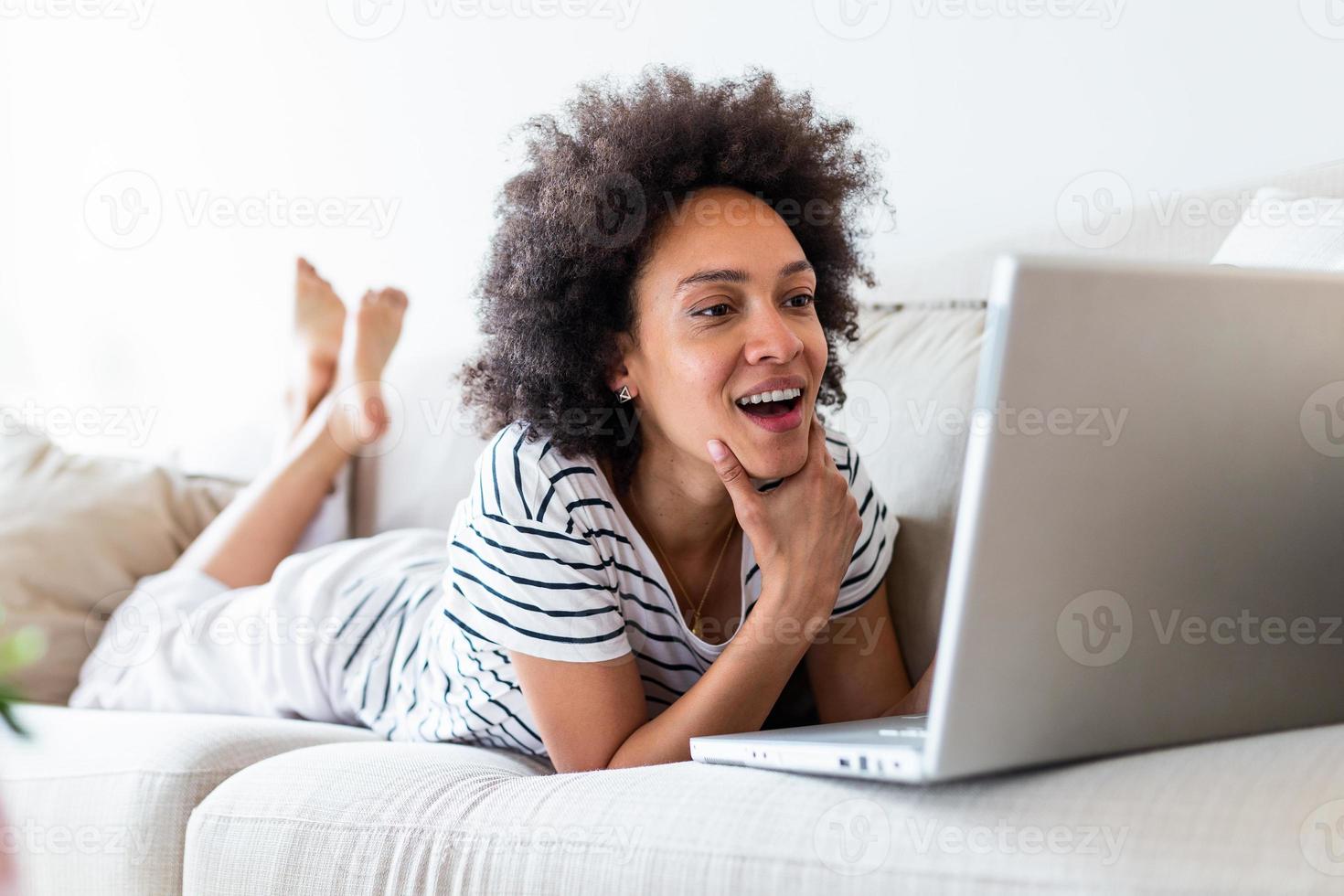 Beautiful woman freelancer noting information for planning project doing remote job via laptop computer. Girl laughing while reading email on modern laptop device . photo