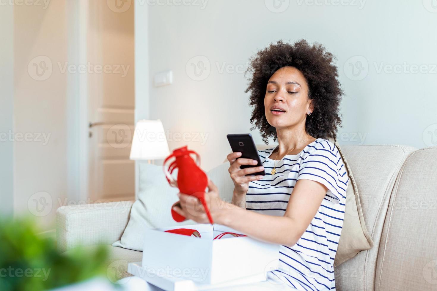 Young woman feeling excited with a new shoes, unpacking purchases and taking photo with phone at home. posting them on social media