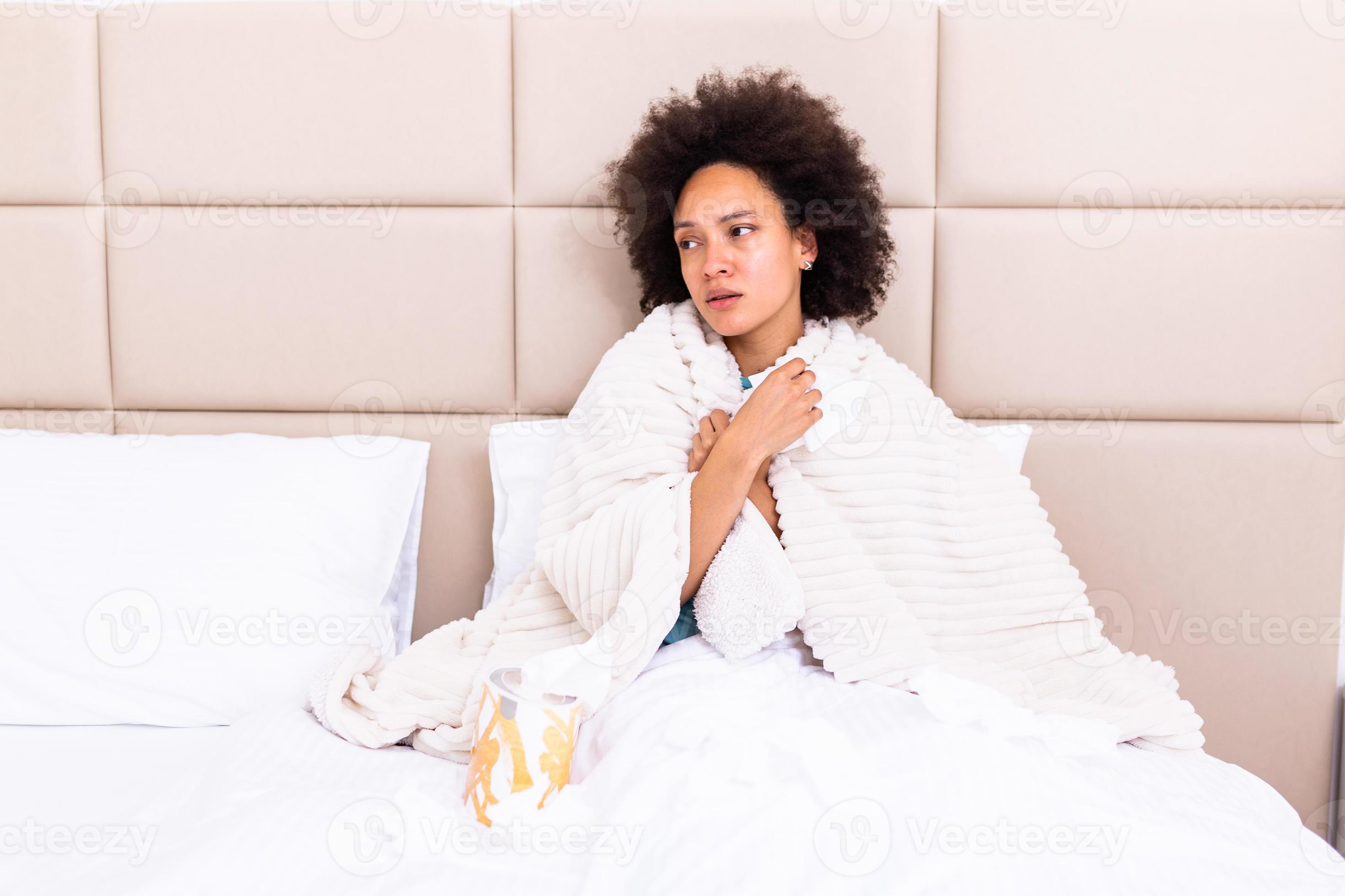 Sick young african woman feeling cold covered with blanket sit on bed