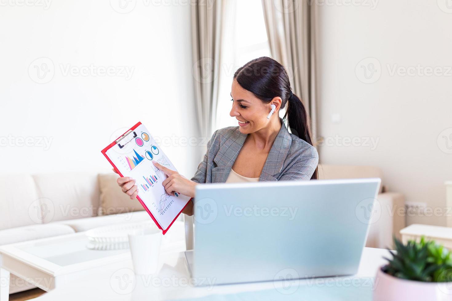 Focused businesswoman presenting charts and graphs on video call online. business, technology and people concept, businesswoman with papers having video conference by laptop computer at office photo
