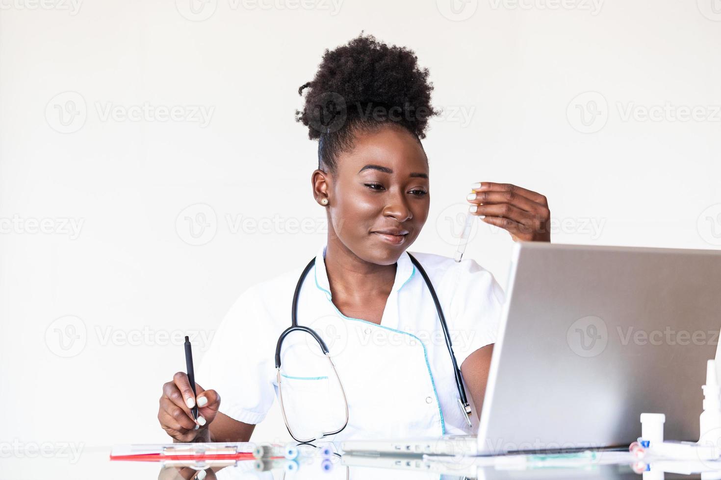 Female doctor in white coat holding blood test tubes in hands while wrapped up in work at modern lab. Female life science professional holding glass cuvette. Healthcare and biotechnology concept. photo