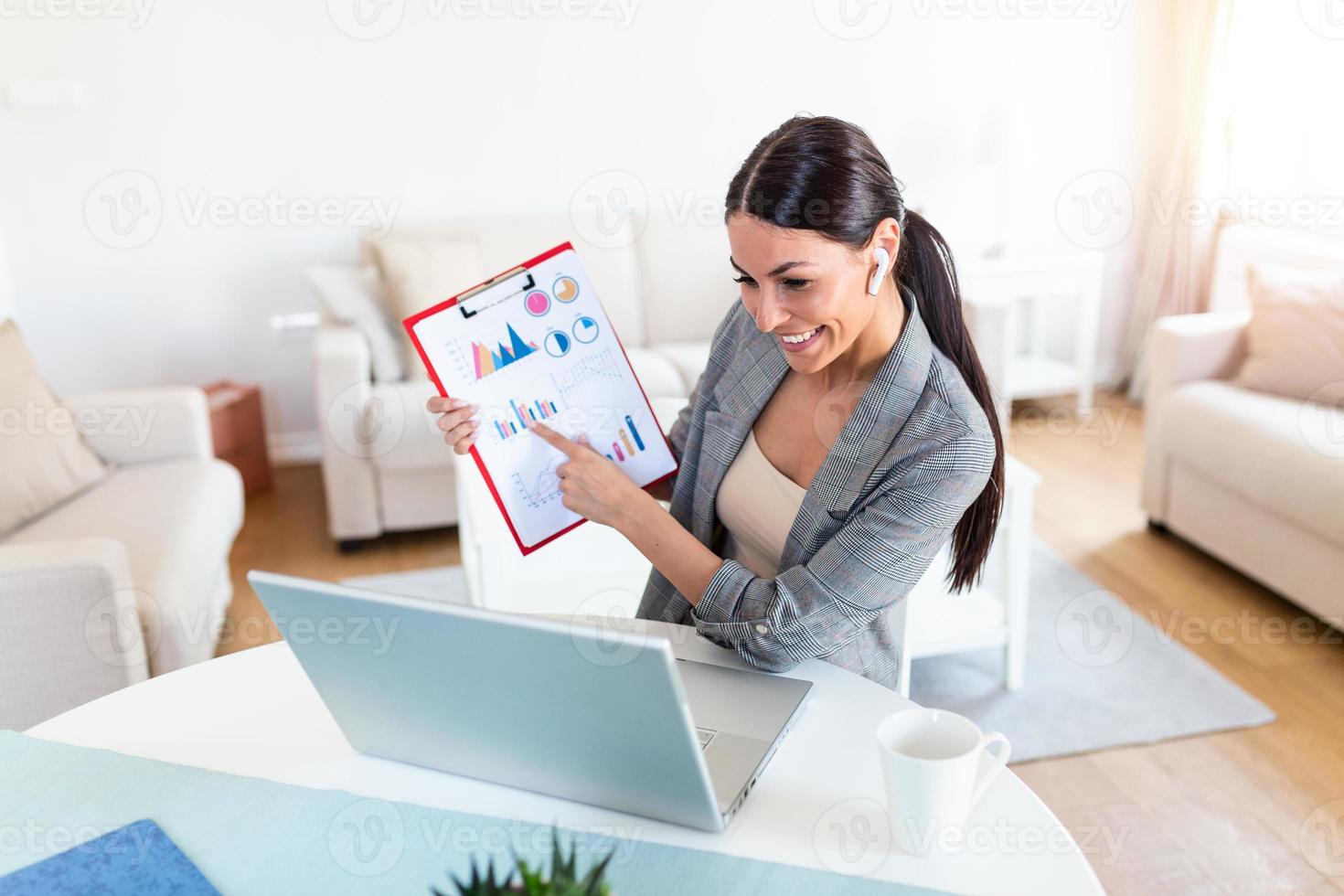 Focused businesswoman presenting charts and graphs on video call online. business, technology and people concept, businesswoman with papers having video conference by laptop computer at office photo
