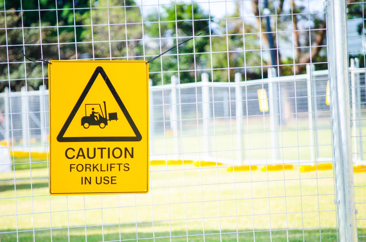 Caution sign for forklifts in use attached to the steel fence. photo
