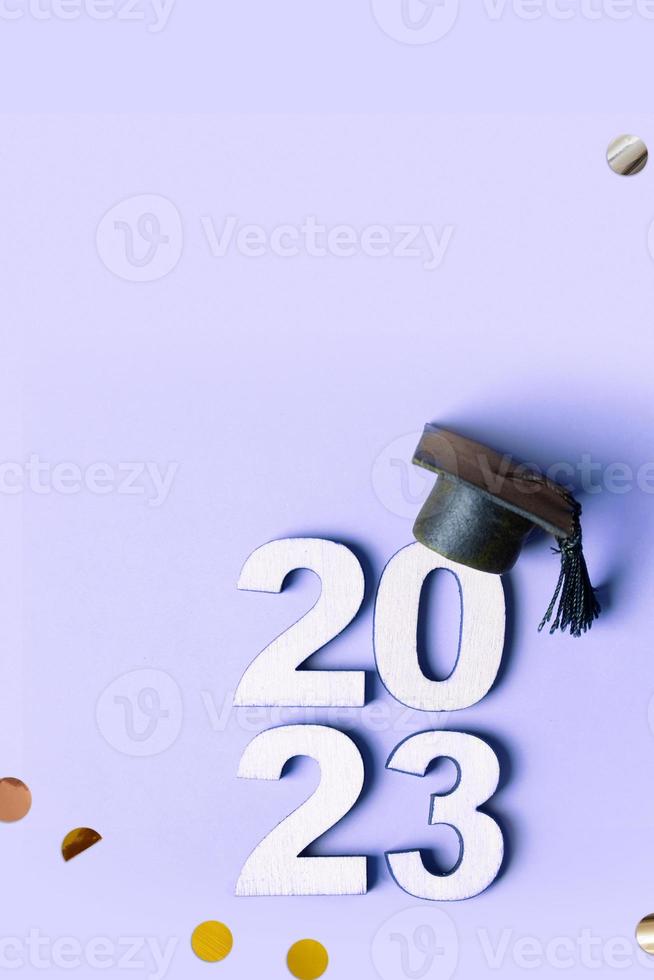 de madera número 2023 con graduado gorra y mosca oropel en púrpura antecedentes. clase de 2023 concepto. foto