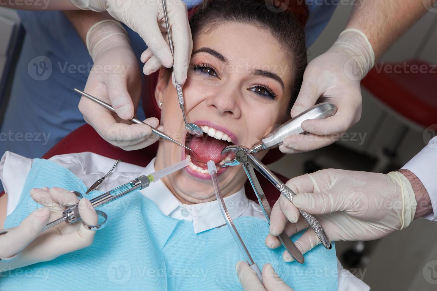 dentista con asistente y paciente a dental clínica. odontología. de cerca de un hembra paciente teniendo su dientes examinado por dentista foto