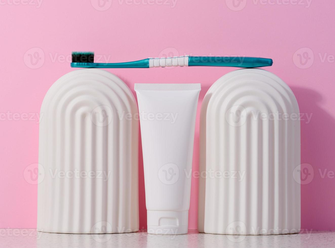 blanco el plastico pasta dental tubo y cepillo de dientes en un rosado antecedentes. foto
