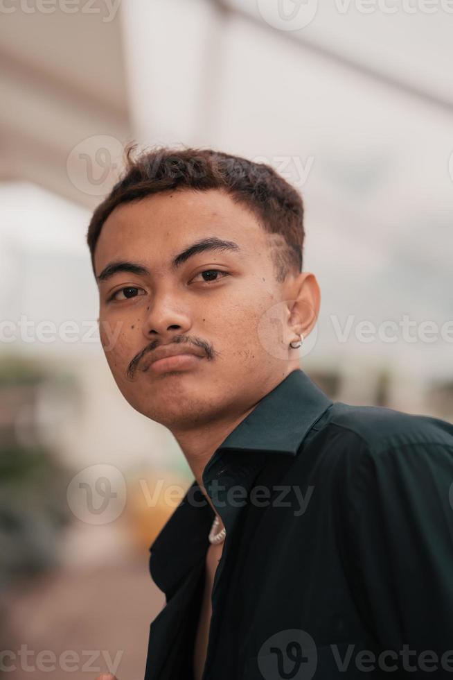 an Asian man with a handsome face and mustache wearing a black shirt while relaxing photo