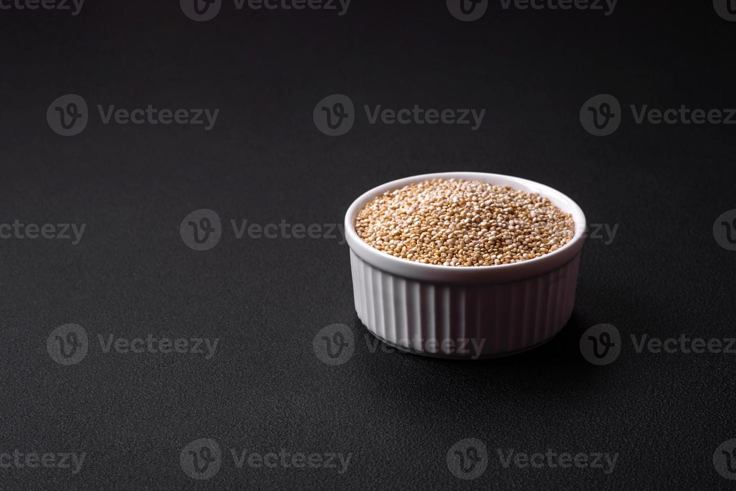 Wholesome raw quinoa in a bowl on a dark concrete background photo