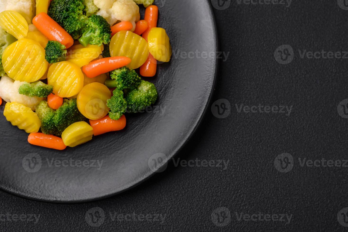 delicioso Fresco vegetales al vapor zanahorias, brócoli, coliflor en un negro plato foto