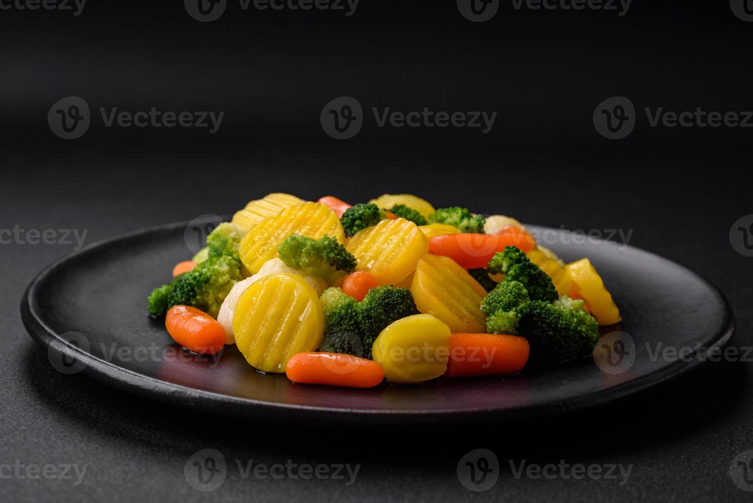 Delicious fresh vegetables steamed carrots, broccoli, cauliflower on a black plate photo
