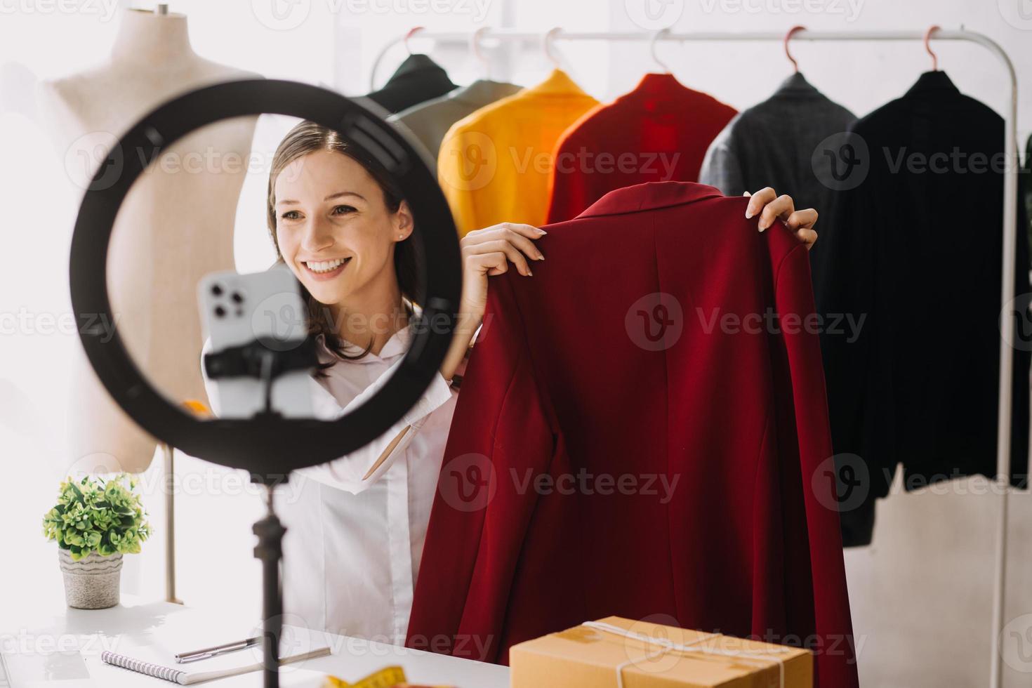 Fashion blogger concept, Young women selling clothes on video streaming.Startup small business SME, using smartphone or tablet taking receive and checking in studio photo