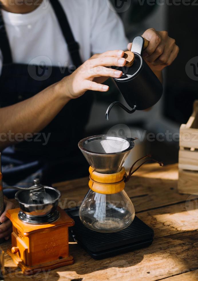 Professional barista preparing coffee using chemex pour over coffee maker and drip kettle. Alternative ways of brewing coffee. Coffee shop concept. photo
