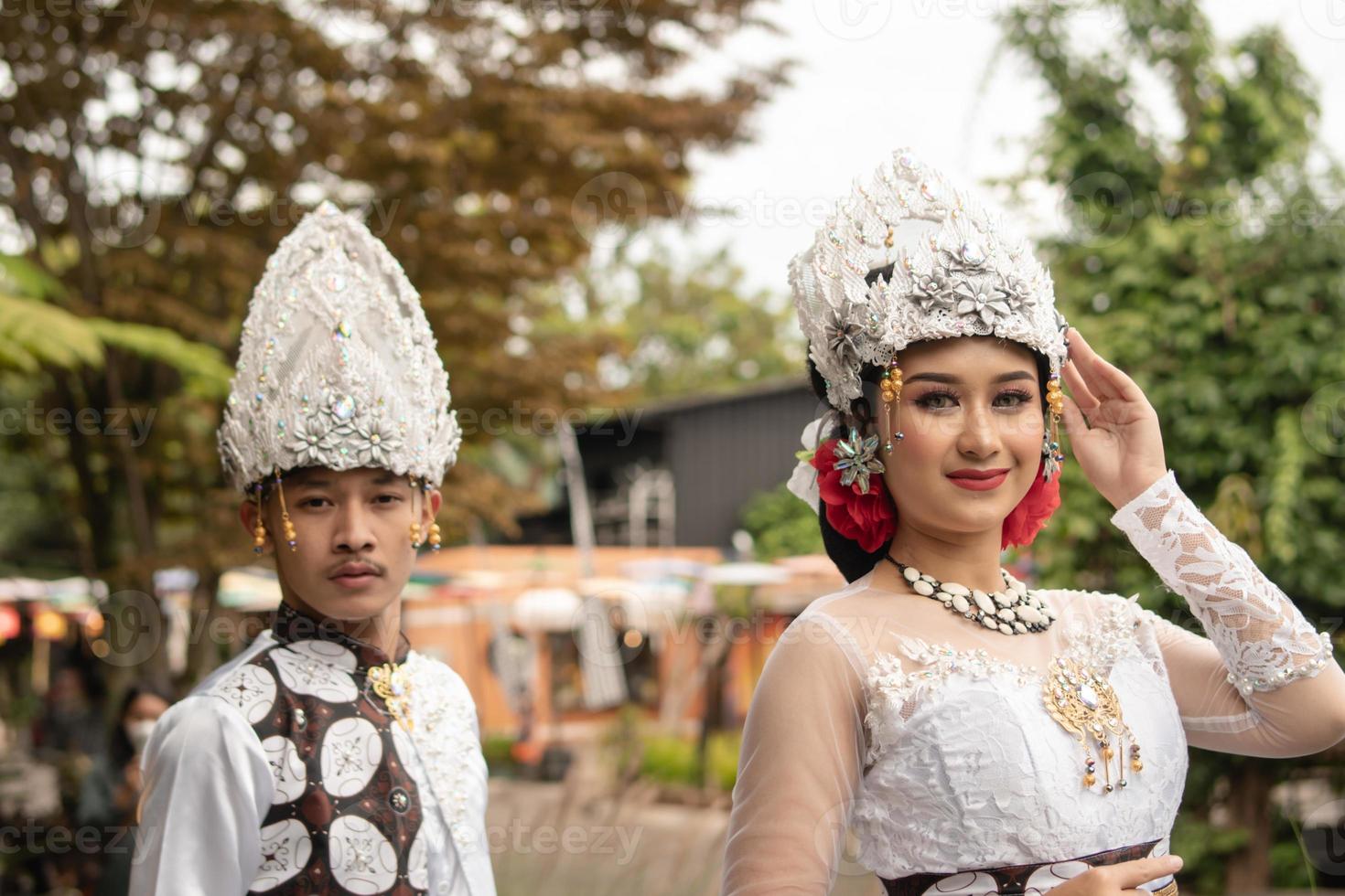 a pair of brides in white clothes standing together very intimately in a tourist park photo